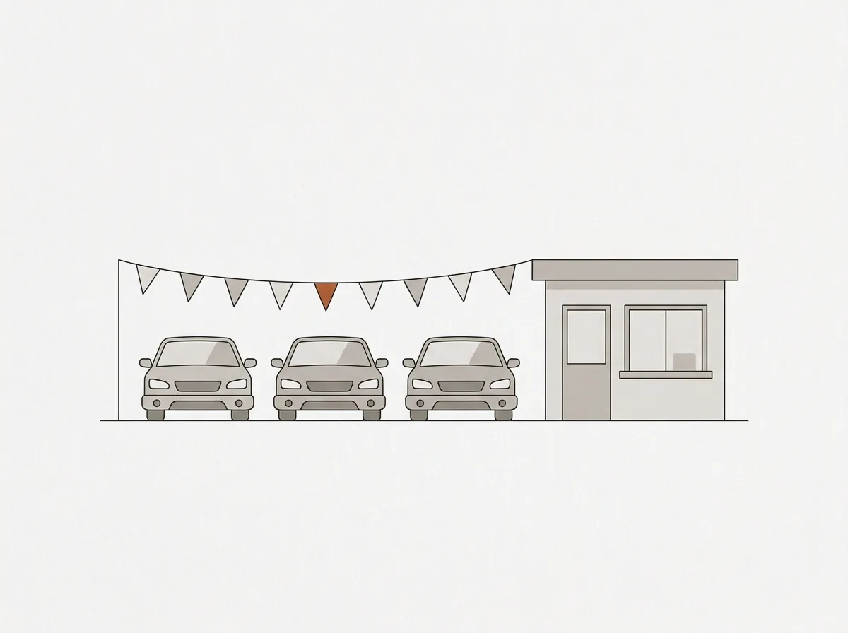 A small dealership lot with three parked cars and a tiny office